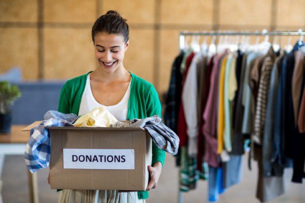 Young woman donating old clothes to charity